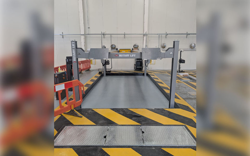 MOT bay quipped with recessed 4-post platform lift featuring black and yellow safety floor markings.