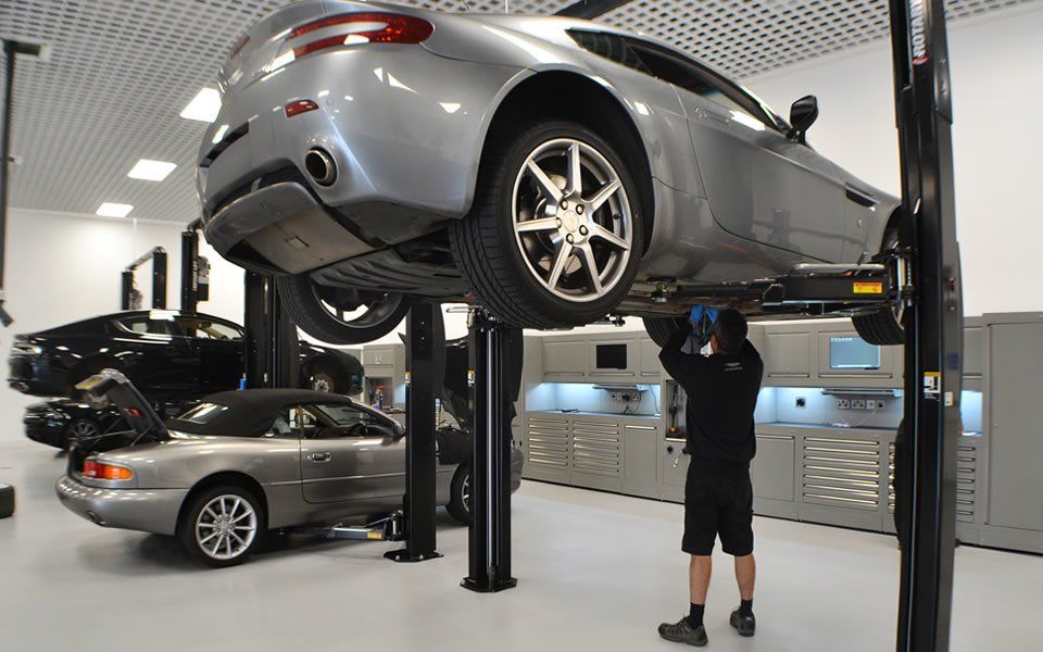 2-post vehicle lift installation operated by workshop engineer at Aston Martin Cheltenham