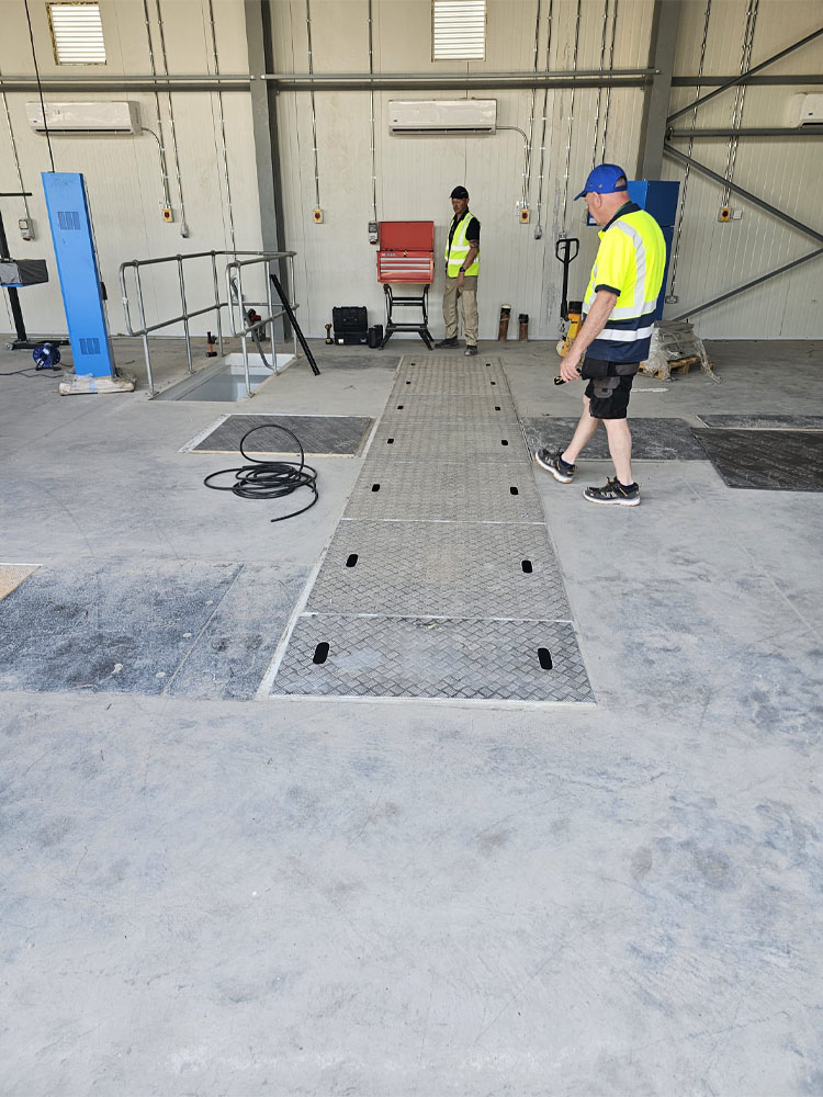 In-ground vehicle inspection pit and ATF test lane fitted inside of new military vehicle workshop.