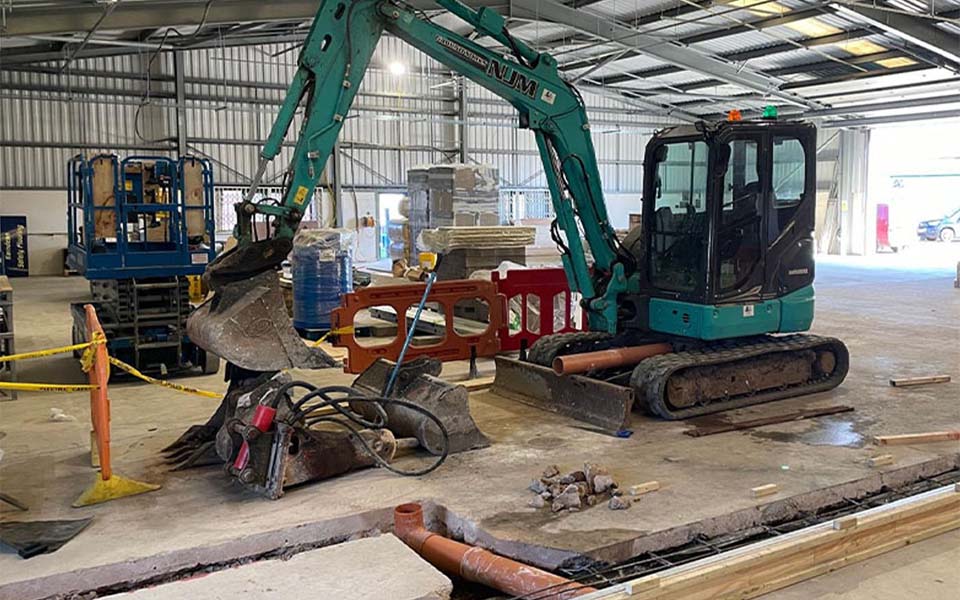 Green heavy digging machinery inside of NWAS workshop depot