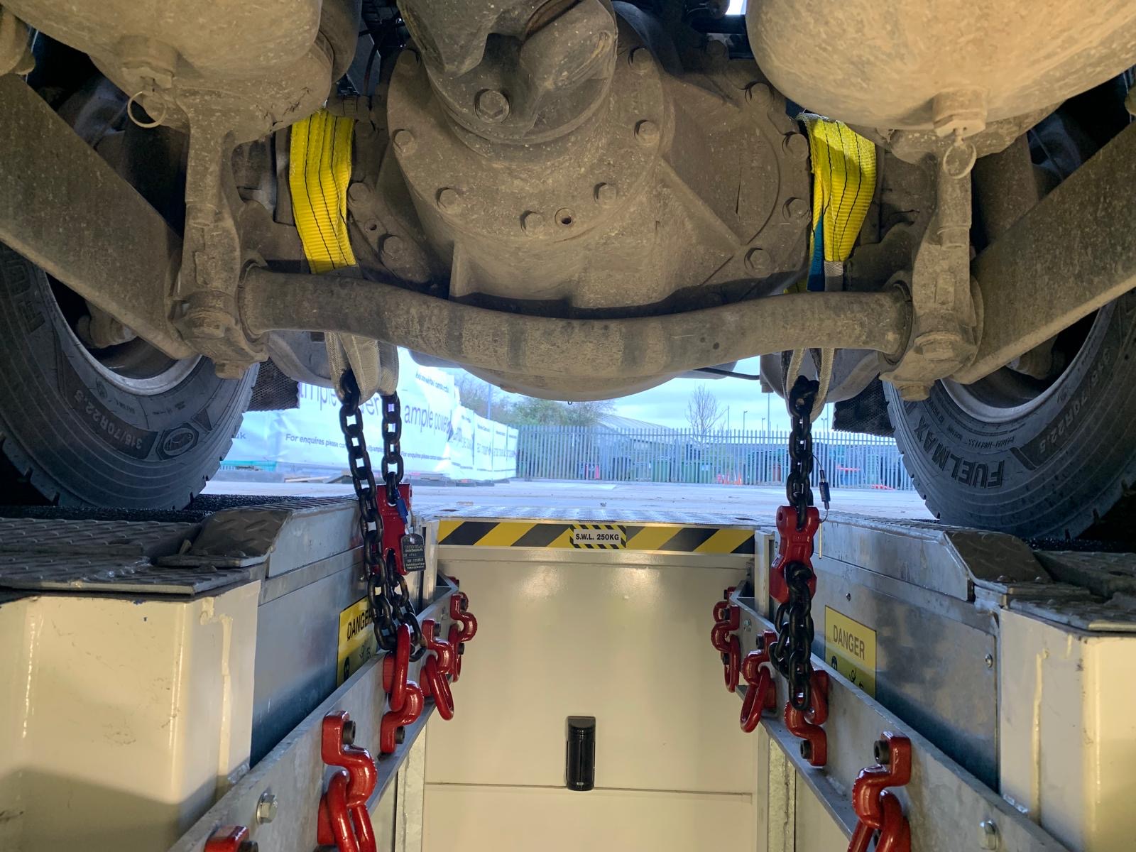 Underside of HVG vehicle connected with red chains to undertake a brake test.