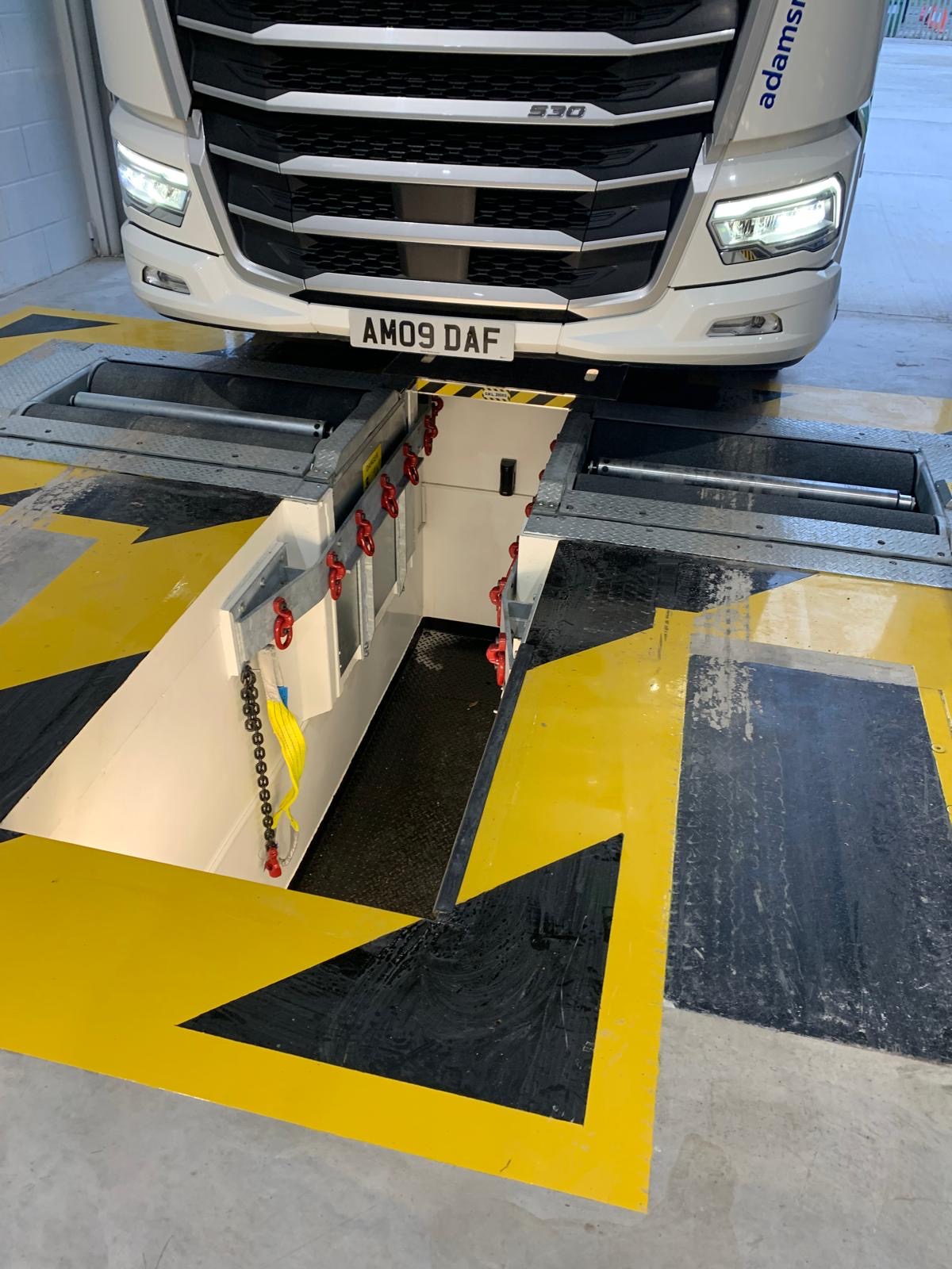 HGV parked in front of commercial brake tester featuring black and yellow safety markings.