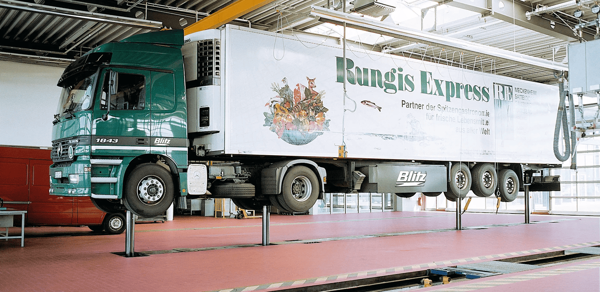 Photo of heavy goods vehicle being lifted by ground mounted workshop lift